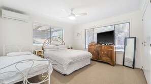 Een slaapkamer met een bed, nachtkastjes, een kledingkast, een televisie en een plafondventilator.