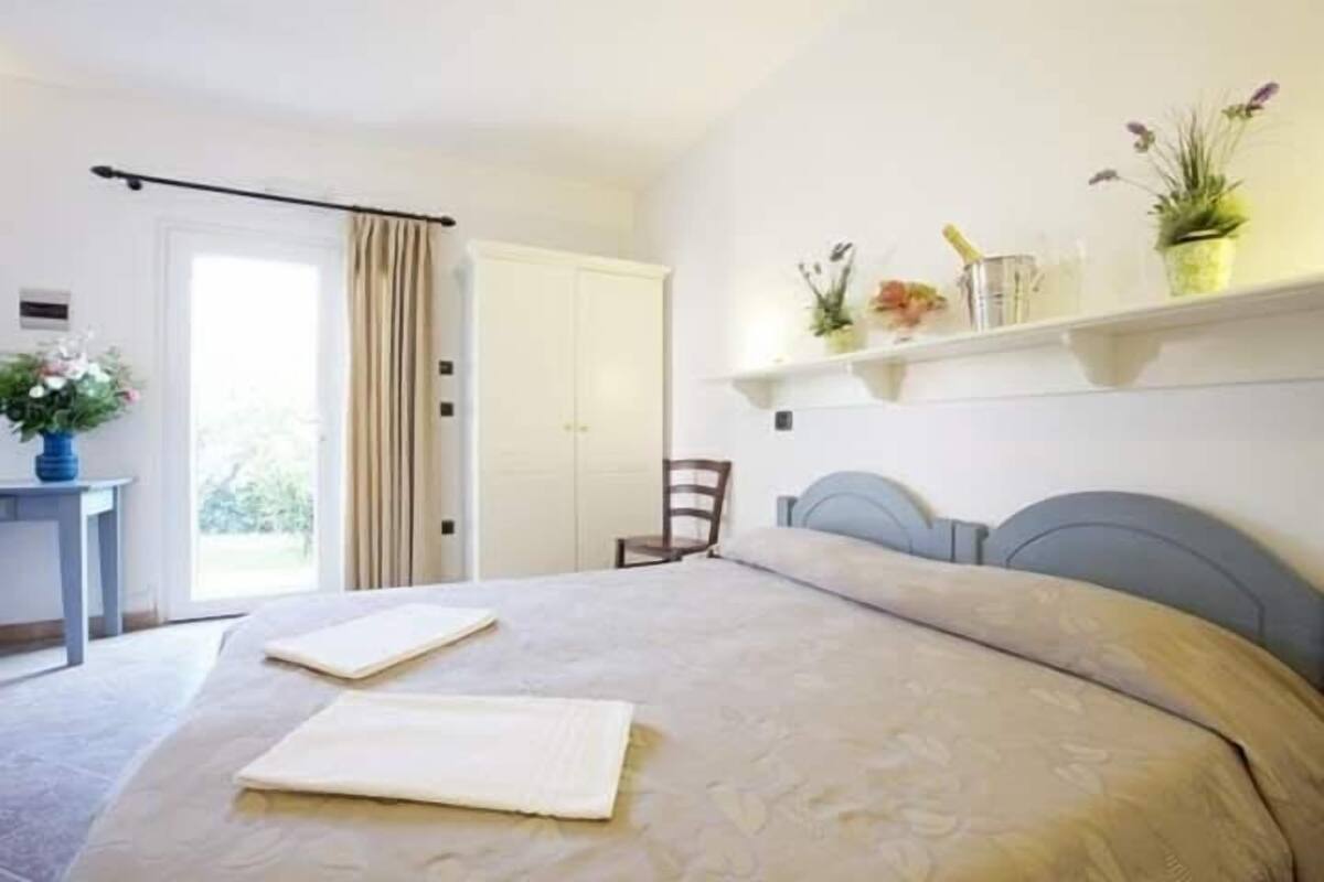 Ein Schlafzimmer mit Bett, Stuhl, Schreibtisch und einem Regal mit Pflanzen.