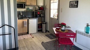 A compact kitchen with wooden cabinets, a microwave, a coffee maker, and a small refrigerator.