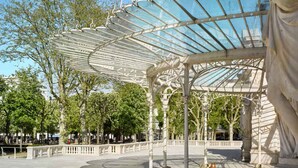 A covered pavilion with a glass roof, columns, and statues.