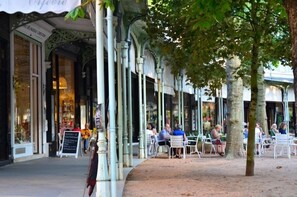 A café with outdoor seating, white chairs, and a covered area with columns.