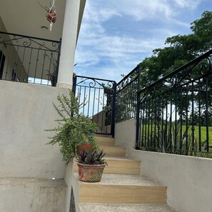 A staircase leading to a gated entrance with potted plants and a clear sky. - House + Kitchen + Pool (San Ignacio)