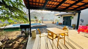 A covered outdoor area with a pool, a table with chairs, and potted plants. - Casa Parota 2 Apartments (San Ignacio)