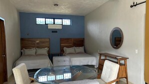 A bedroom with two beds, a glass table, and a round mirror. - Casa Parota 2 Apartments (San Ignacio)