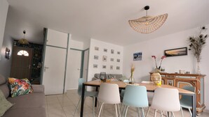 A dining area with a wooden table, four chairs, a sofa, and a decorative cabinet. - Renovated house located 5 minutes from the beach and playground, close to shops. (Le Crotoy)