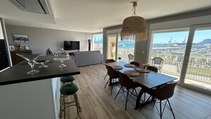 Una cucina moderna con zona pranzo, ampie finestre e vista sulla città, illuminata da un lampadario.
