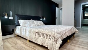Una camera da letto moderna con un letto grande, pareti scure e pavimento in legno.