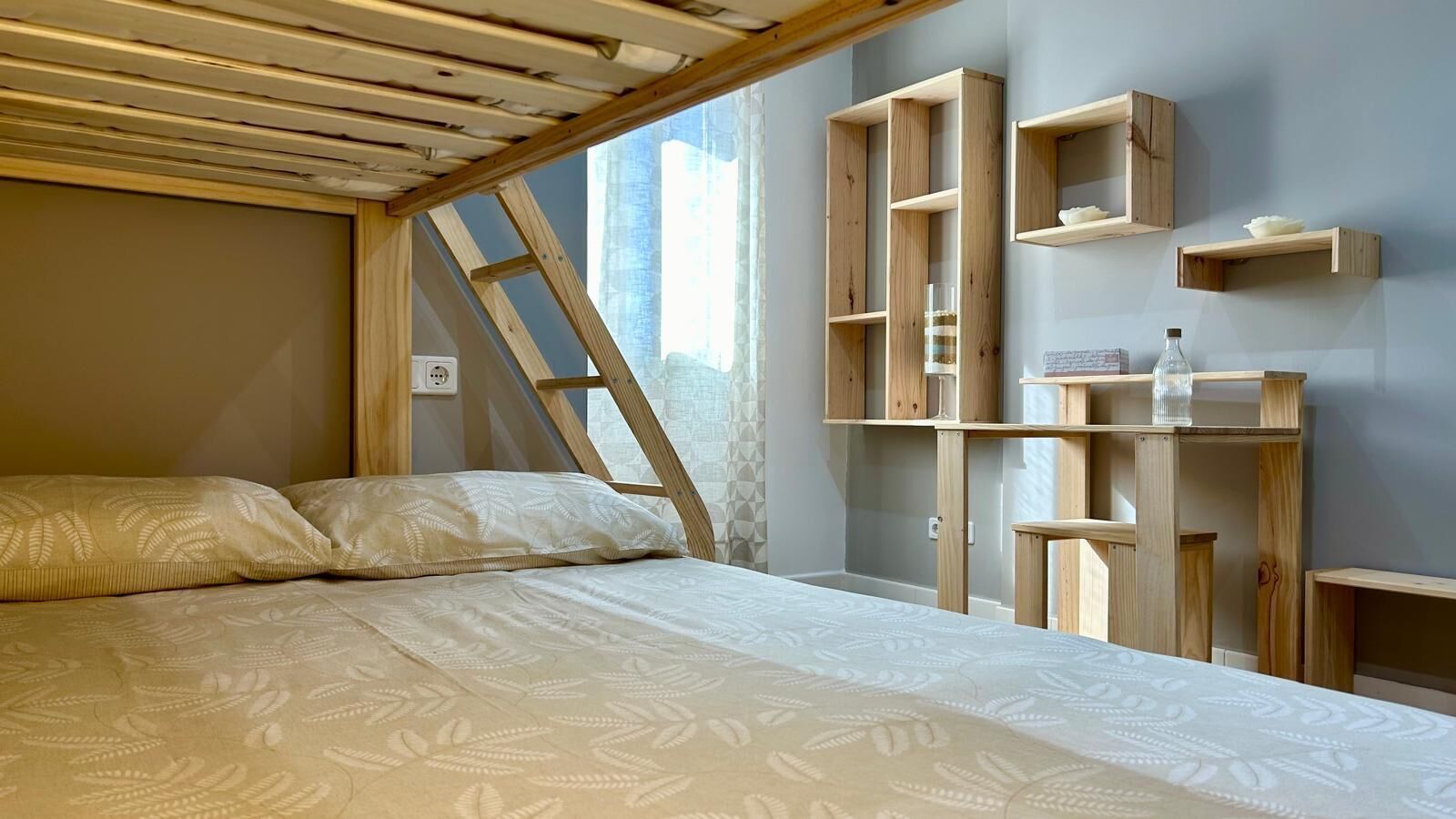 A bedroom with a bed, wooden shelves, and a ladder.