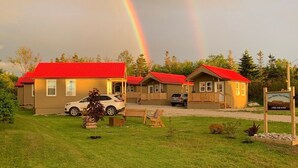 Una hilera de cabañas con techos rojos, un césped y un letrero que dice 'Cottage Home Tiny Chalet'.