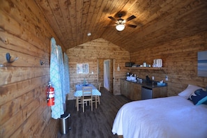 Une cabane confortable avec un coin repas, une kitchenette et un lit.