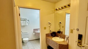 A hotel bathroom with a sink, mirror, and toilet. - Western Budget Plus Killam Krossing (Killam)