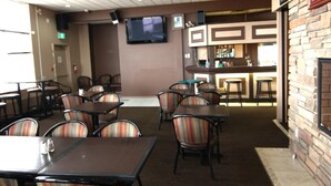 A restaurant with tables and chairs, a bar area, and a television mounted on the wall. - Western Budget Plus Killam Krossing (Killam)