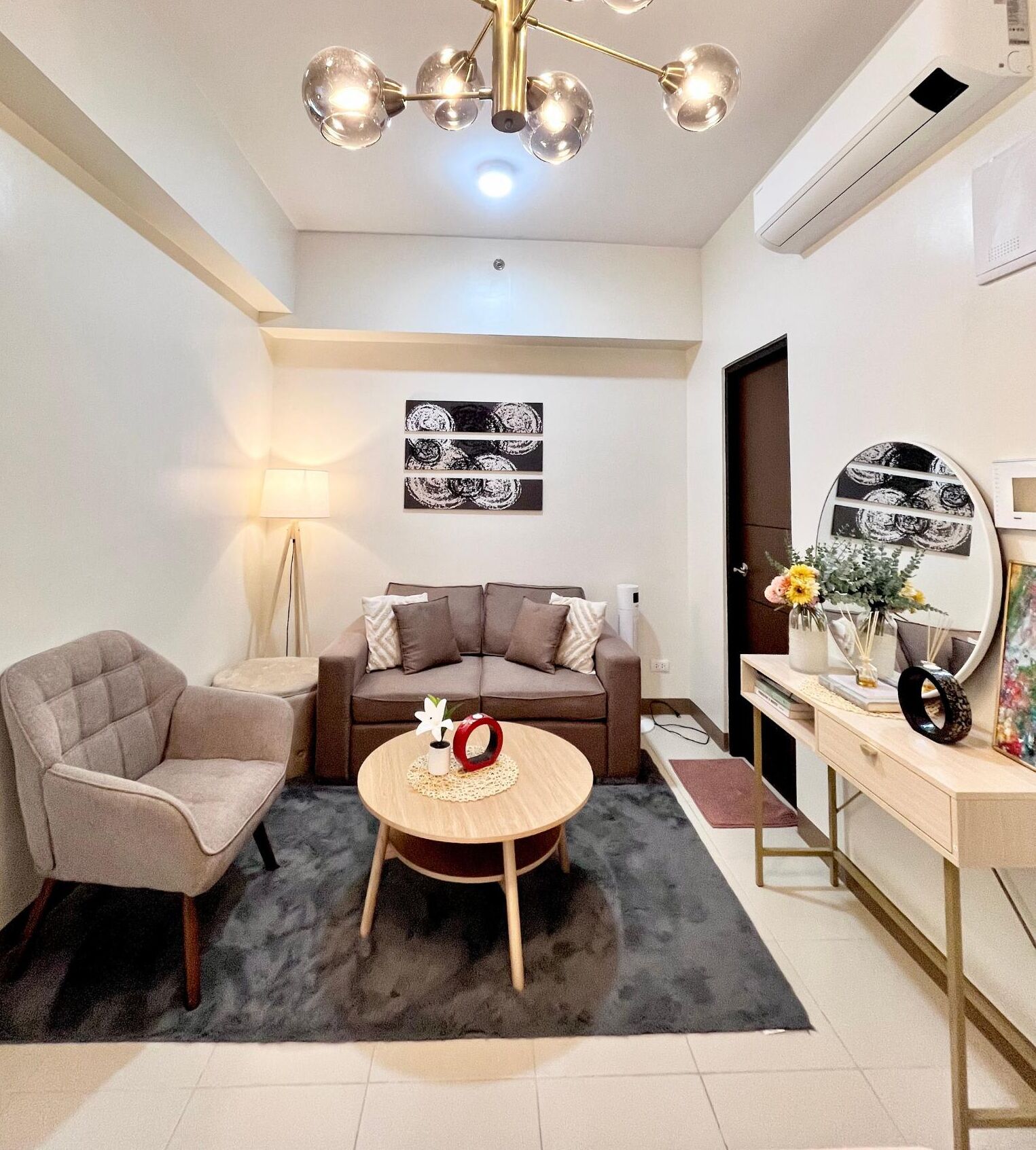 A modern living room with a sofa, armchair, coffee table, and a decorative mirror.