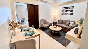 Uma sala de estar moderna com área de jantar, sofá, mesa de centro e luminária.