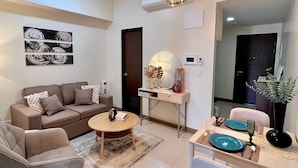 Uma sala de estar moderna com sofá, mesa de centro, mesa de jantar e objetos decorativos.