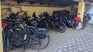 A covered bike parking area with multiple bicycles and helmets. - Gasthaus zum Hirschen (Muhr am See)