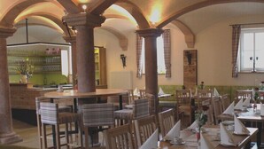 A restaurant with high arched ceilings, wooden tables and chairs, and a bar area with a green counter. - Gasthaus zum Hirschen (Muhr am See)