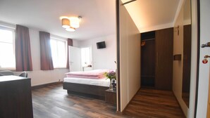 A bedroom with a bed, a desk, a chair, a wardrobe, and a TV on the wall. - Gasthaus zum Hirschen (Muhr am See)