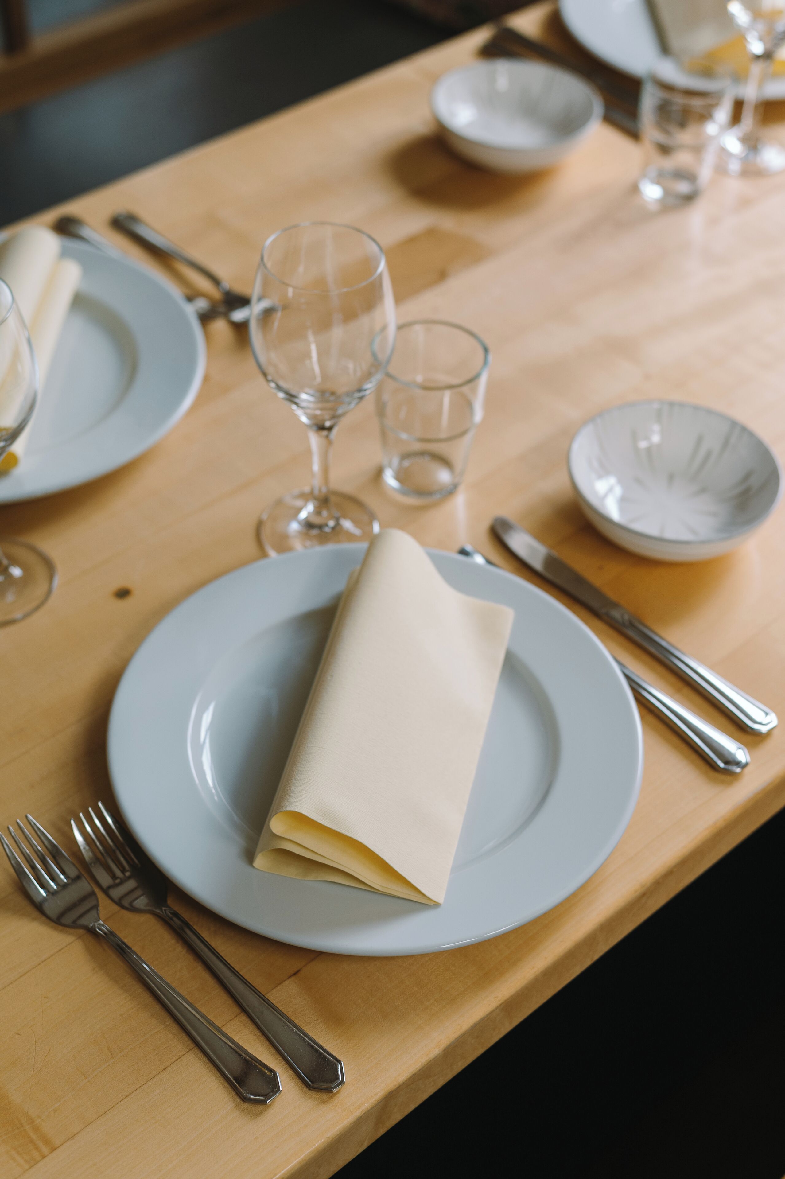 A neatly set dining table with plates, cutlery, and glasses.