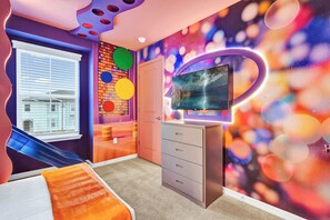 Un dormitorio moderno con cama, cómoda, televisor y ventana con persianas.