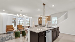 A spacious kitchen with a large island, dark cabinetry, and modern pendant lighting.