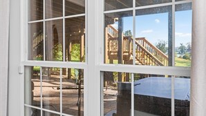 A view through a window of a building with a wooden deck and a stone wall.
