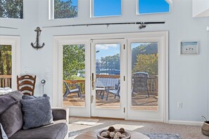 Et værelse med en stor skydedør, der fører ud til en terrasse med udendørs møbler.