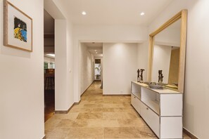 Stylish hallway leads to a room with a large mirror and a vanity with a bowl sink.