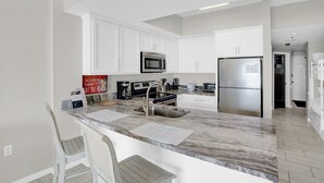 Una cocina moderna con armarios blancos, electrodomésticos de acero inoxidable y encimera de mármol.