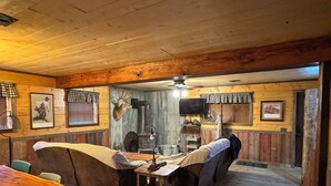 A rustic interior with wooden walls, a fireplace, a mounted deer head, and a bar area. - Hidden Cabin in the Woods (Pawhuska)