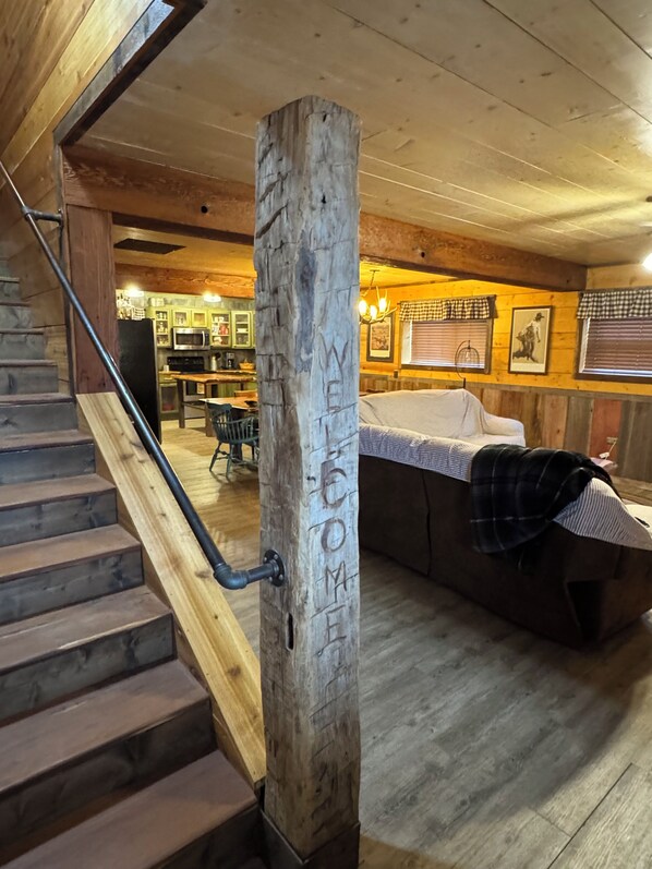 A wooden staircase leading to a kitchen area with a 'WELCOME' sign on a post.