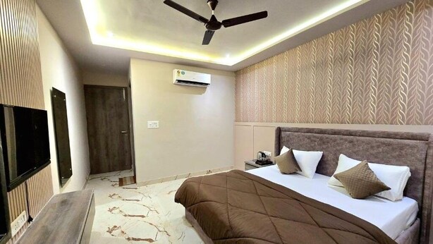 Une chambre d’hôtel moderne dotée d’un grand lit, d’un ventilateur de plafond, d’un climatiseur et d’un papier peint à motifs.