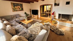 A cozy living room with a wooden ceiling, a large sofa, a television, and a fireplace. - Cozy chalet in the Swiss Alps with Heidi bed. Pet friendly! (Amden)