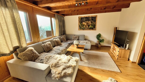 A cozy living room with a sectional sofa, a coffee table, and a flat-screen TV. - Cozy chalet in the Swiss Alps with Heidi bed. Pet friendly! (Amden)