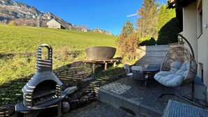 A patio with a stone oven, outdoor seating, and a view of a mountain. - Cozy chalet in the Swiss Alps with Heidi bed. Pet friendly! (Amden)