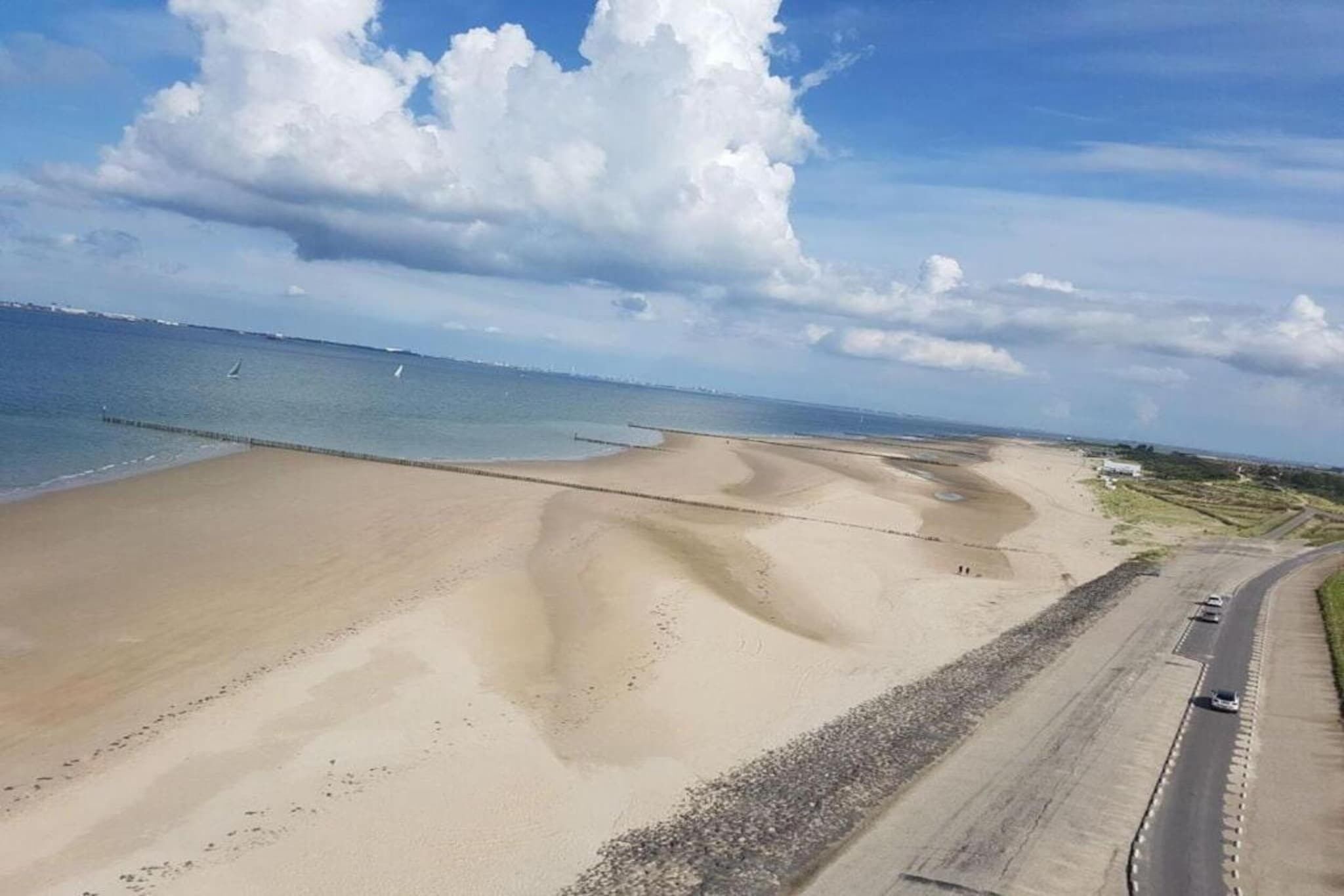 Une plage bordée d’une route qui la longe.