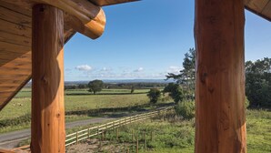 A wooden structure with a view of a rural landscape, including fields and a road. - Traditional Scandinavian/north American Log Home (Ripon)
