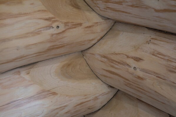 A close-up of wooden logs with visible grain patterns and knots. - Traditional Scandinavian/north American Log Home (Ripon)
