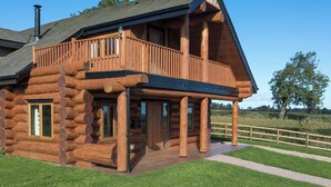 A log cabin with a balcony, large windows, and a chimney. - Traditional Scandinavian/north American Log Home (Ripon)