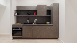 A modern kitchen with a built-in oven, a sink, and a coffee maker.
