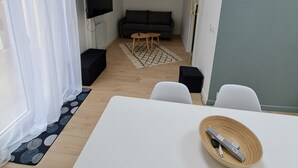 A modern living room with a sofa, a coffee table, and a TV mounted on the wall. - Cosy, bright house close to amenities in Mordelles (Mordelles)