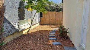 A garden with mulch, stepping stones, a small tree, and a wooden fence. - Cosy, bright house close to amenities in Mordelles (Mordelles)
