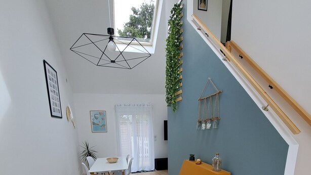A modern kitchen with a dining area, wooden flooring, and a staircase with a blue wall. - Cosy, bright house close to amenities in Mordelles (Mordelles)