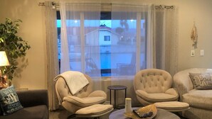 A living room with a sofa, two armchairs, a coffee table, and a view through a window. - Driftwood Cove Lake House – Waterfront, Pet-Friendly, Private Dock in Helendale (Helendale CA)