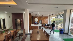 A hotel lobby with a reception desk, seating area, and a large dining table. - Hotel Ishwar Palace (Danta Ramgarh)