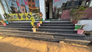 A set of outdoor steps leading to a building with a yellow signboard displaying food images. - Hotel Ishwar Palace (Danta Ramgarh)