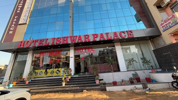 A hotel with a modern glass facade, a prominent sign reading "HOTELISHWAR PALACE," and a staircase leading to the entrance. - Hotel Ishwar Palace (Danta Ramgarh)