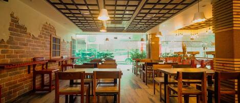 Een restaurant interieur met bakstenen muren, houten tafels en stoelen, en een plafond met rasterpatroon.