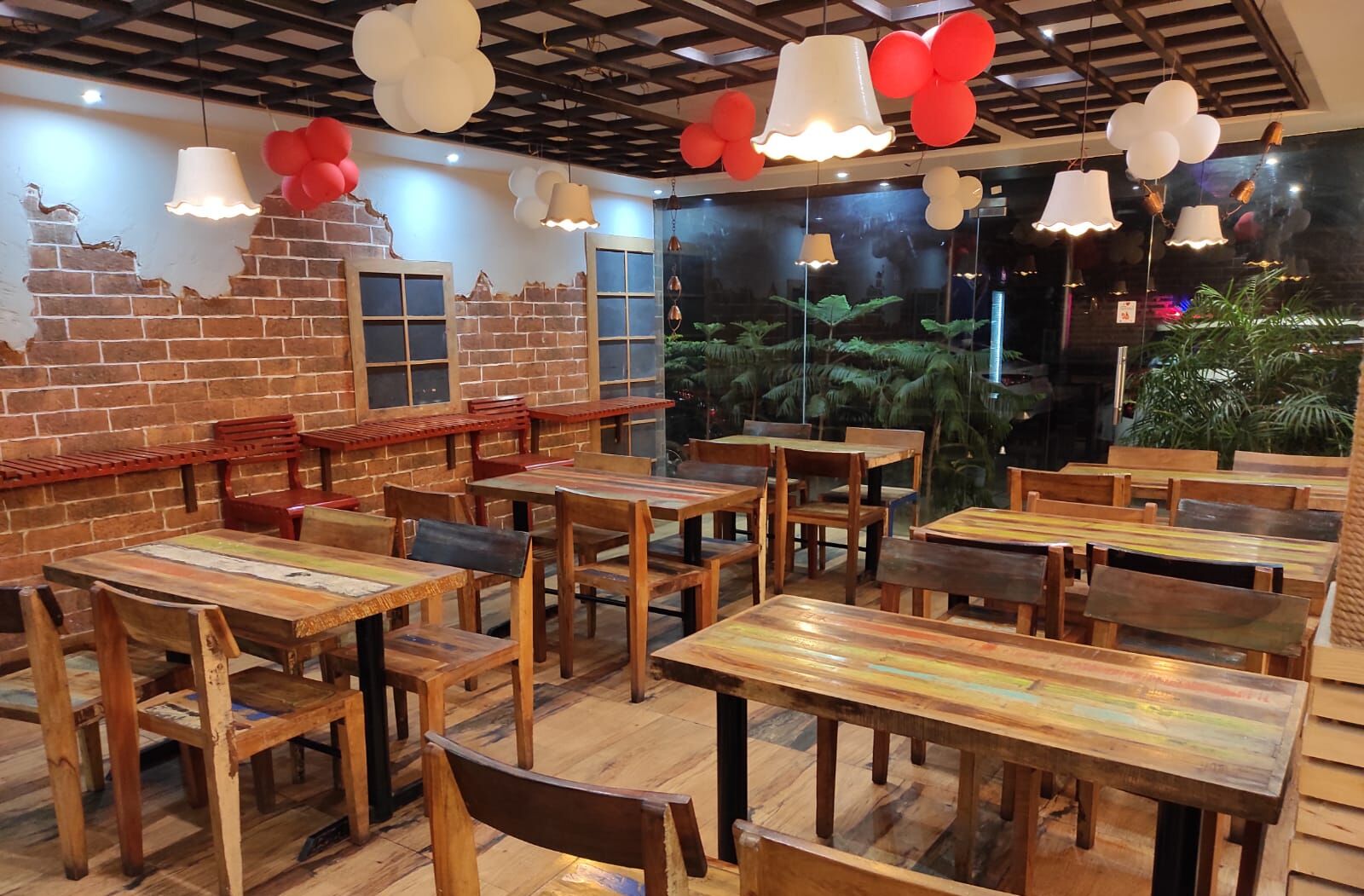 Un restaurant avec des tables et des chaises en bois, un mur en briques et des luminaires suspendus.