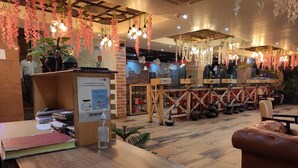 A cozy cafe with wooden tables and hanging floral decorations.